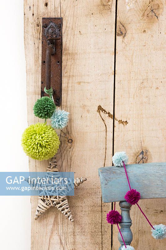 Pompons en laine de différentes tailles suspendus à une poignée de porte