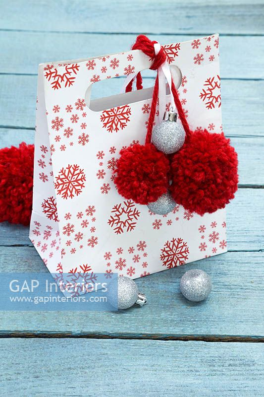 Sac cadeau de Noël décoré de boules argentées et de pompons rouges en laine