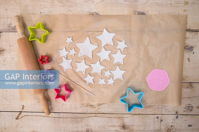 Fabrication d'étoiles en argile - Une variété d'étoiles de tailles différentes découpées dans la pâte à modeler, avec de petits trous ajoutés pour la suspension