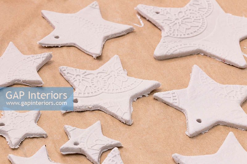 Fabrication d'étoiles en argile - Une variété d'étoiles de tailles différentes découpées dans la pâte à modeler, avec de petits trous ajoutés pour la suspension