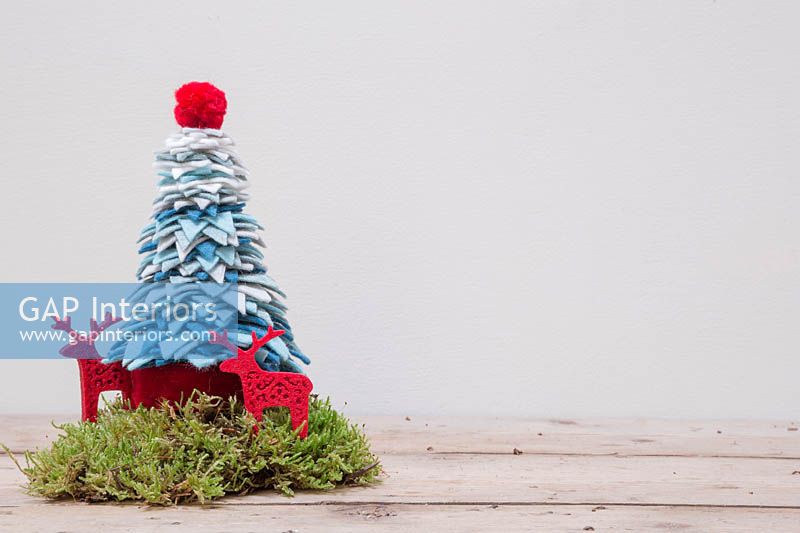 Une décoration d'arbre de Noël en fil et feutre coloré avec de la mousse et des rennes en feutre
