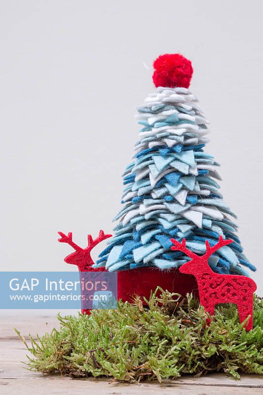 Une décoration d'arbre de Noël en fil et feutre coloré avec de la mousse et des rennes en feutre