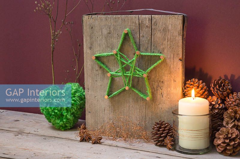 Faire une décoration d'étoile de Noël - Un socle décoratif avec une étoile de laine verte enroulée autour d'ongles de cuivre