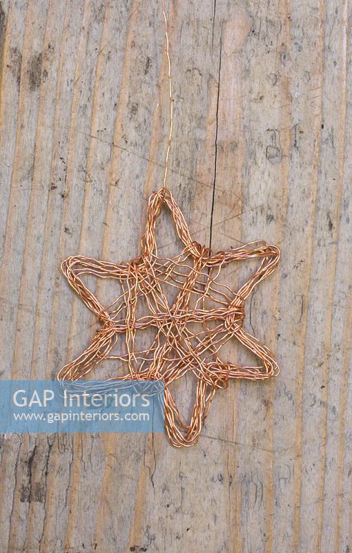 Faire des étoiles en fil de cuivre - décorations finies sur une surface en bois