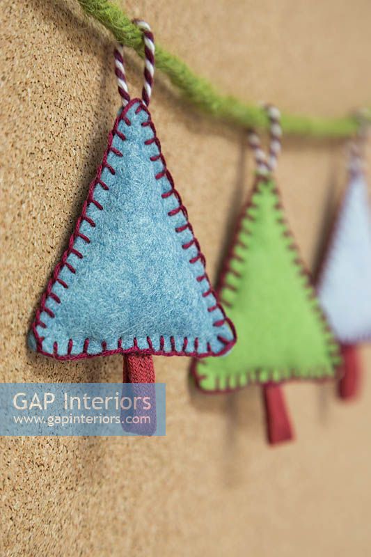 Fabrication de décorations de Noël en feutre cousu - arbres de Noël miniatures en feutre et chaîne décorative, accrochés contre une planche de liège
