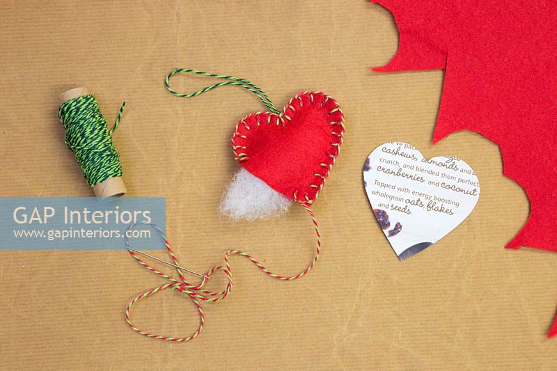 Faire des décorations de Noël - Les matériaux requis sont un modèle de coeur, une aiguille, du fil, de la laine et du feutre