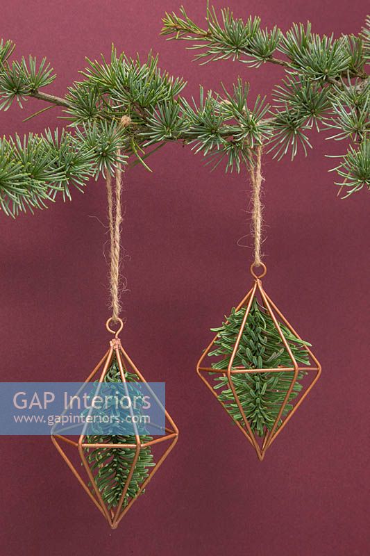 Prismes en cuivre contenant du feuillage de pin, suspendus à l'arbre de Noël