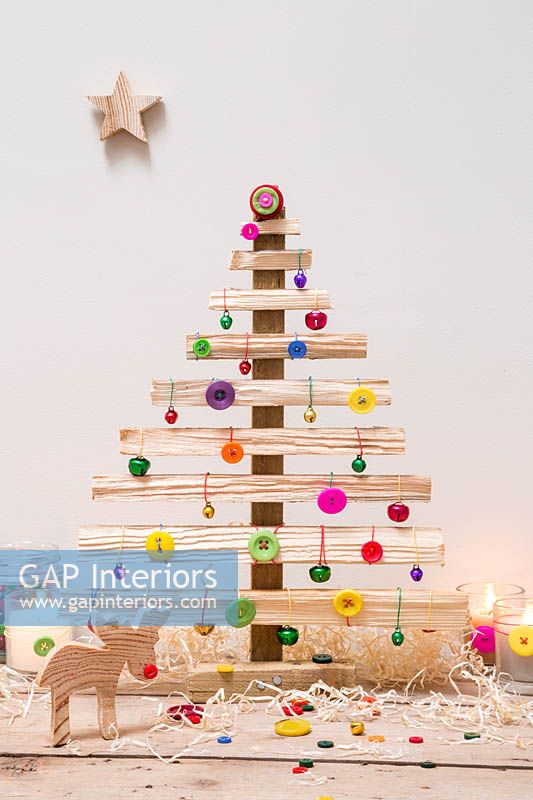 Un sapin de Noël en bois décoré de boutons et de boules de couleur