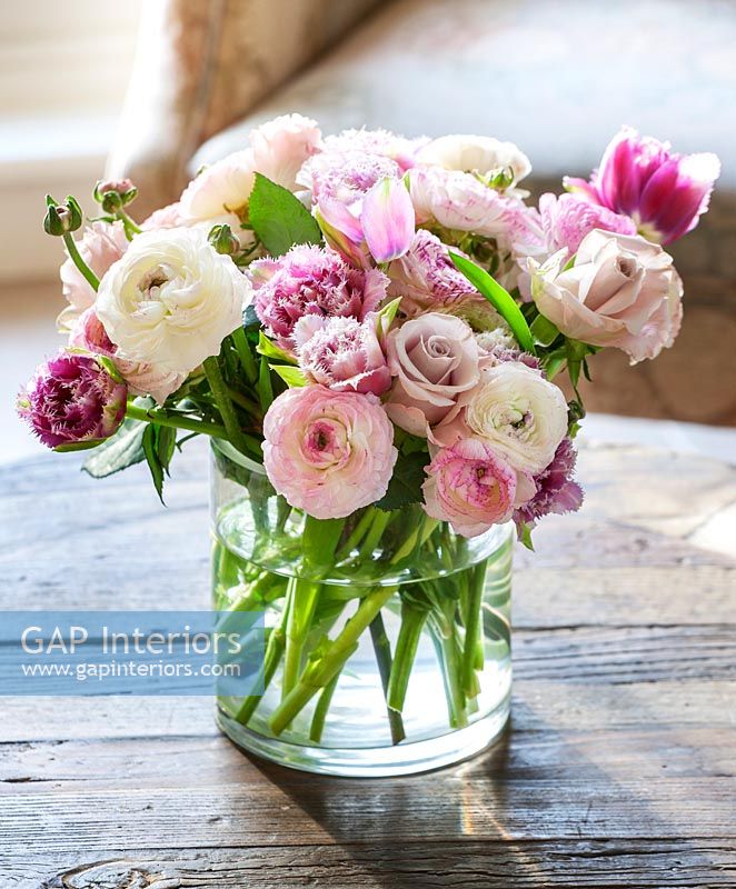 Vase de renoncule, de roses et de fleurs de tulipes sur table basse