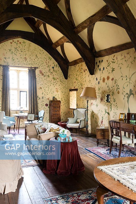 La grande chambre avec un design mural floral peint à la main par Arabella Arkwright et des meubles anciens - Cothay Manor