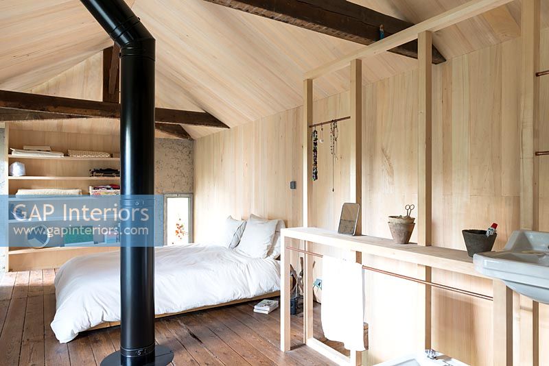 Chambre moderne à aire ouverte avec murs en bois et conduit de fumée exposé