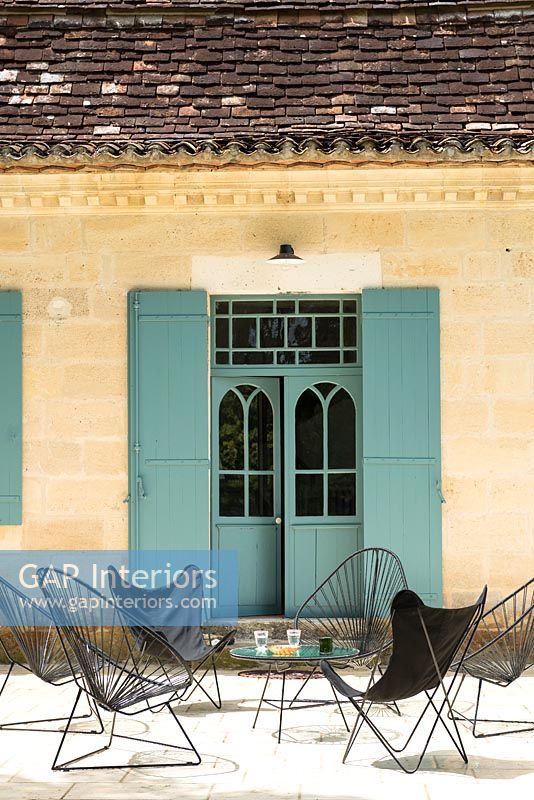 Portes françaises peintes avec volets et chaises de jardin noires modernes