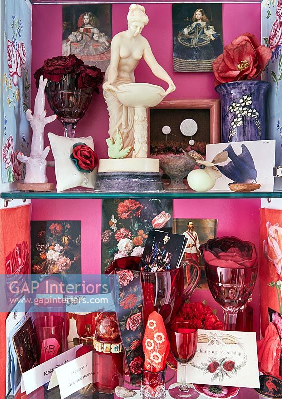 Présentoirs et objets de collection sur des étagères en verre avec des murs peints en rose