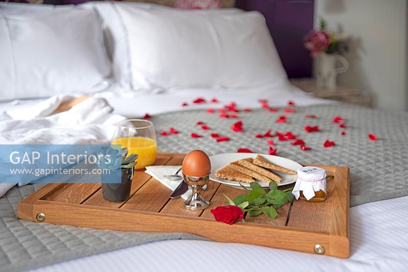 Plateau petit déjeuner sur lit avec pétales de rose et peignoir