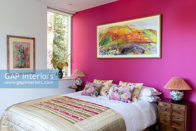 Mur caractéristique rose vif et œuvres d'art colorées dans une chambre moderne
