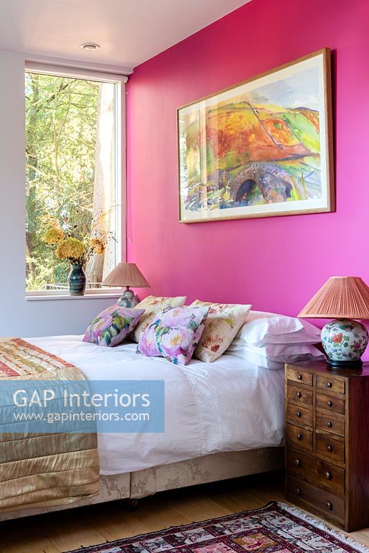 Mur peint rose vif et illustrations dans une chambre moderne