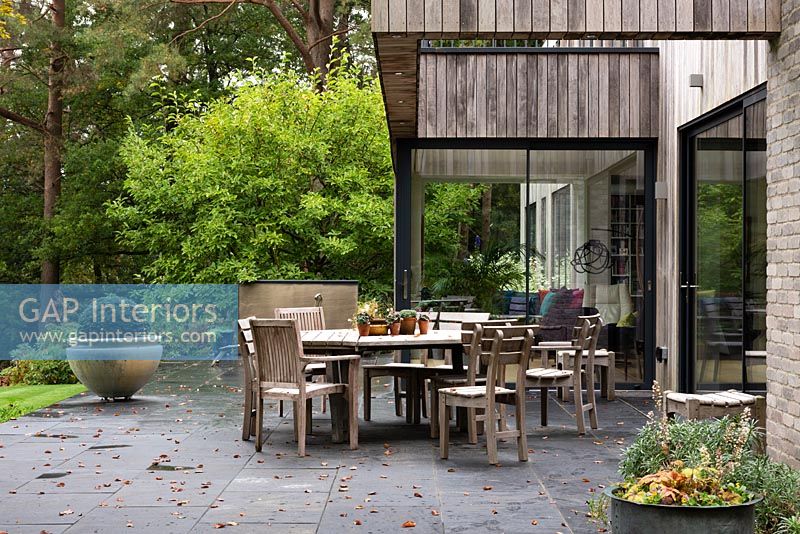 Extérieur de maison moderne dans un jardin boisé avec salon extérieur sur terrasse