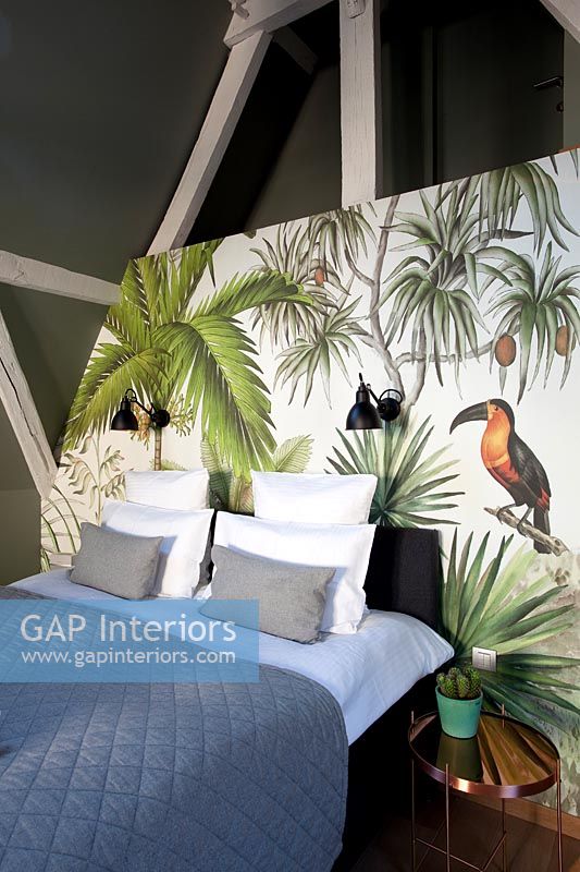 Scène tropicale peinte comme toile de fond au lit dans une chambre moderne