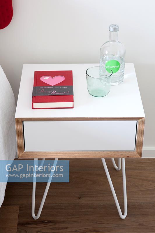 Petite armoire de chevet avec verre d'eau et livre romantique