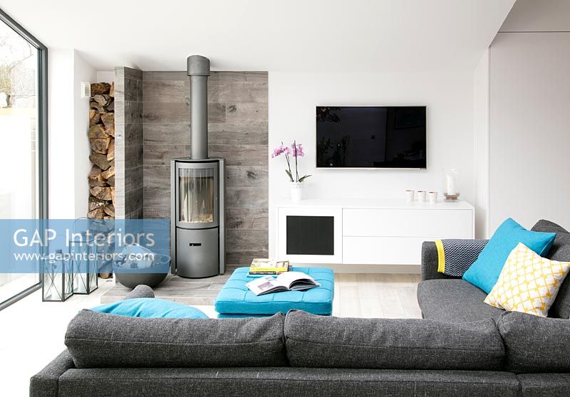 Salon moderne avec poêle à bois et télévision murale