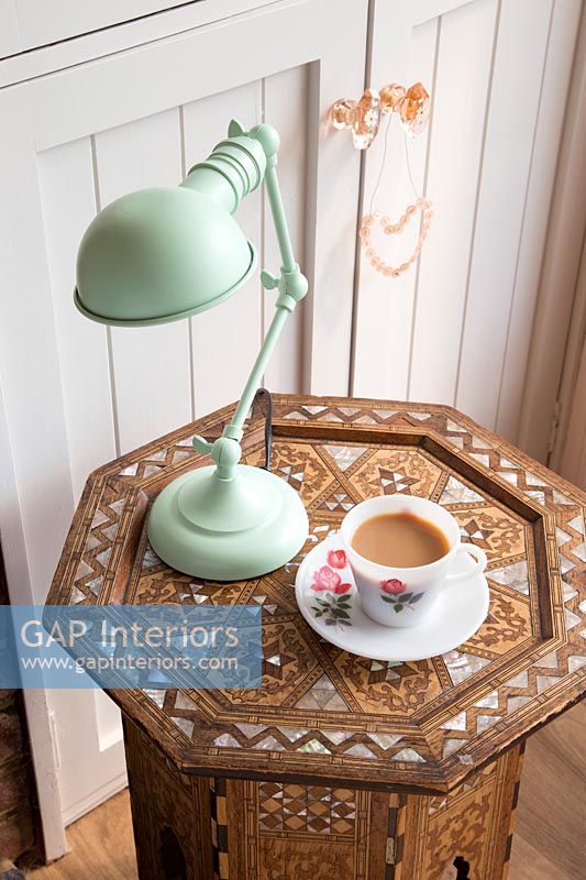 Lampe verte et tasse de thé sur une table en bois décorative