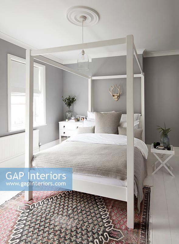 Lit à baldaquin blanc dans une chambre moderne avec des murs peints en gris