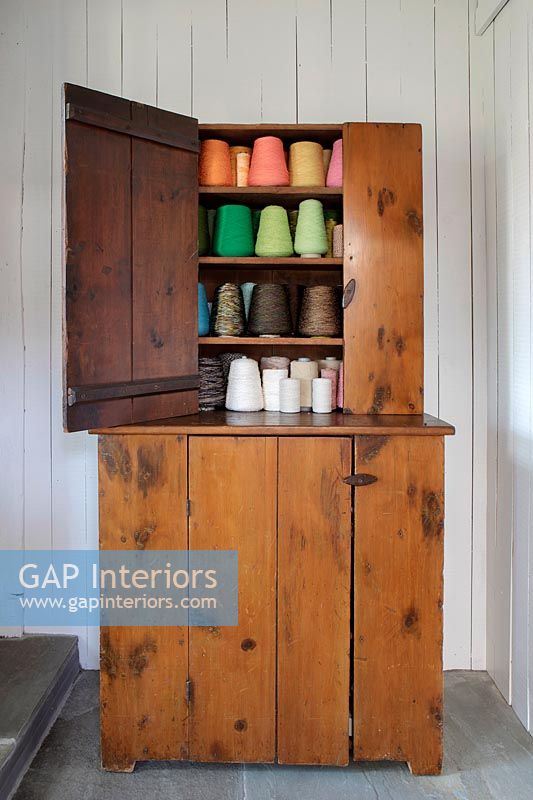 Armoire en bois vintage remplie de bobines de fil colorées