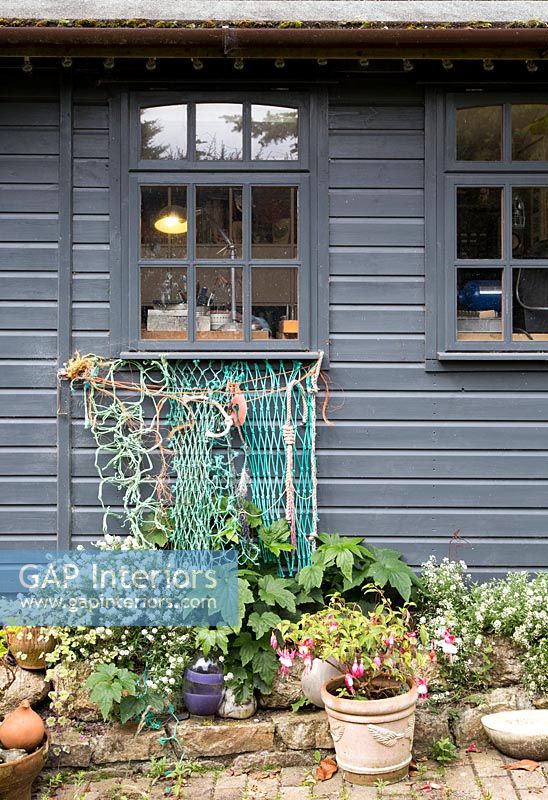 Filet de pêche suspendu au rebord de la fenêtre d'une maison revêtue de bois peint en gris