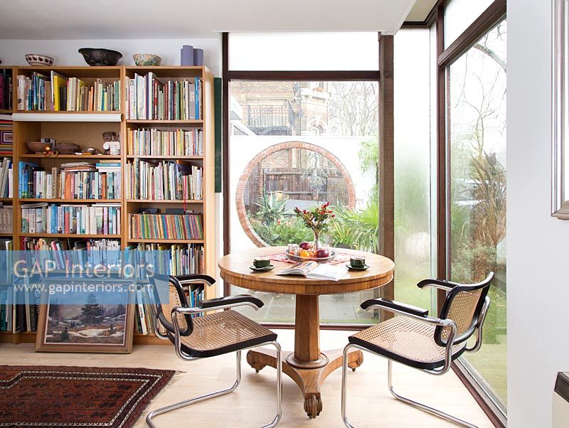 Table circulaire avec chaises en étude avec étagères et grandes fenêtres
