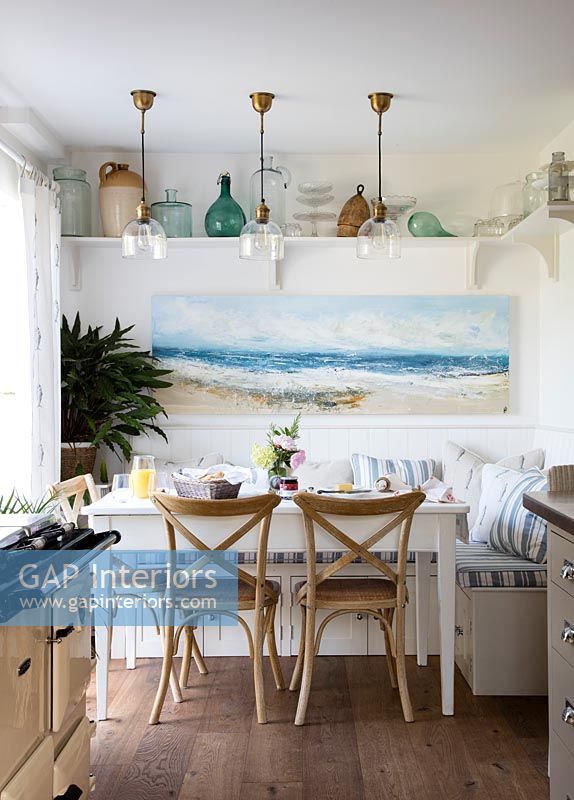 Peinture côtière au-dessus de la table à manger dans une cuisine de campagne moderne