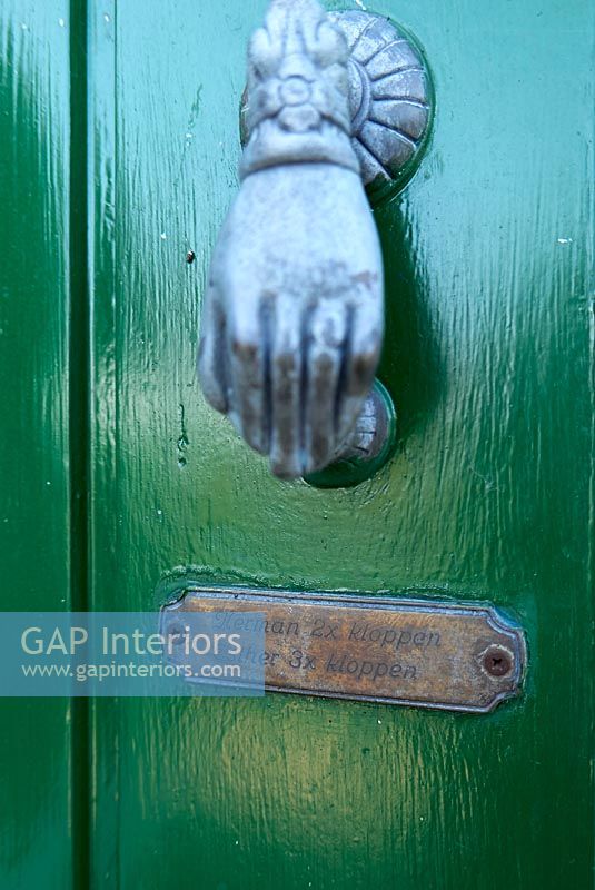 Heurtoir de porte en forme de main et plaque sur la porte d'entrée peinte en vert