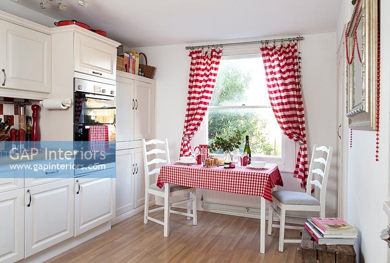Petite table dans une cuisine rouge et blanche de style campagnard moderne