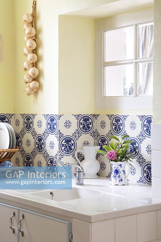 Carreaux décoratifs bleu et blanc derrière un double évier dans la cuisine