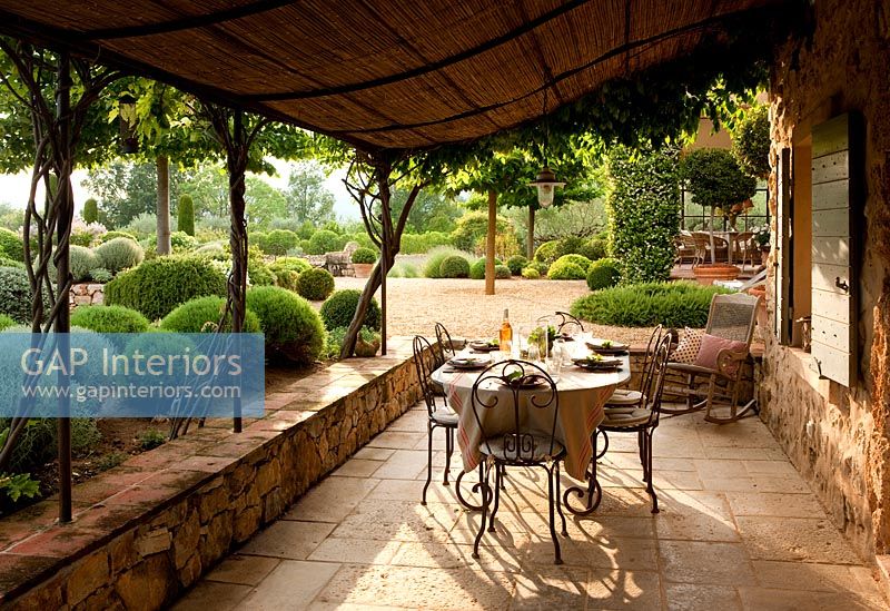 Terrasse couverte avec table à manger donnant sur les jardins à la française