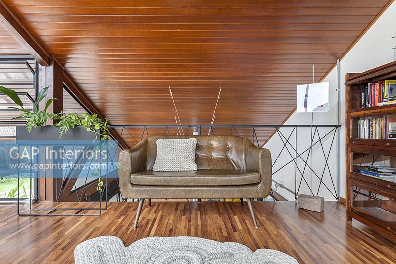 Canapé en cuir dans le salon moderne avec plafond en bois incliné