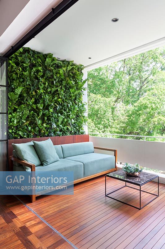 Canapé sur le balcon en bois espace de vie extérieur et mur végétal vert