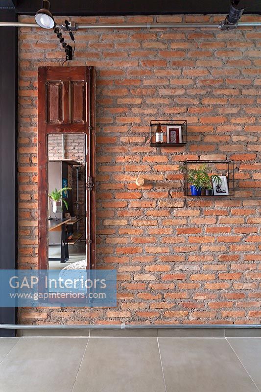 Vieille porte d'armoire en bois miroir montée sur mur de briques