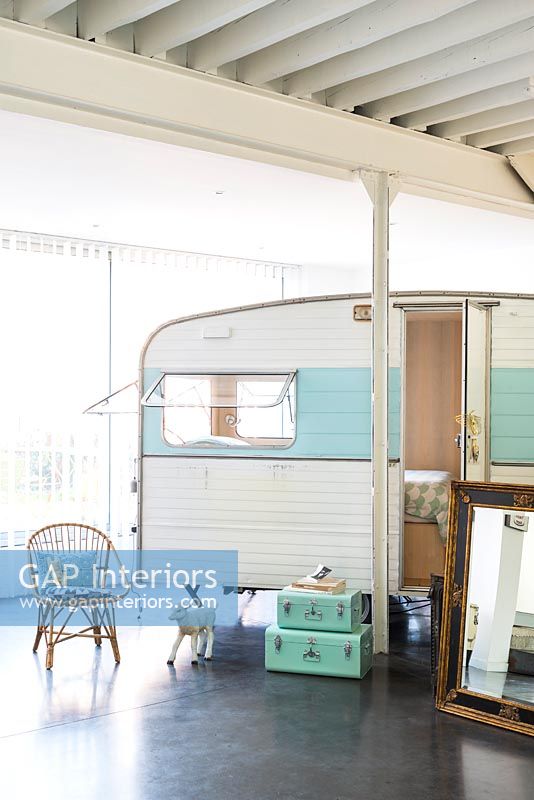Caravane vintage utilisée comme chambre à coucher dans une maison industrielle