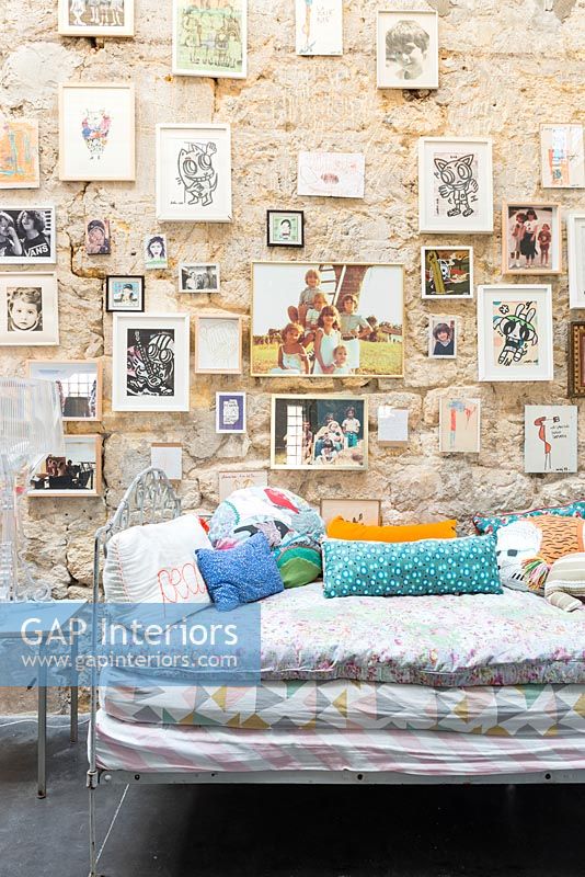 Grand mur de pierre rempli de photos sur lit de repos dans la chambre des enfants