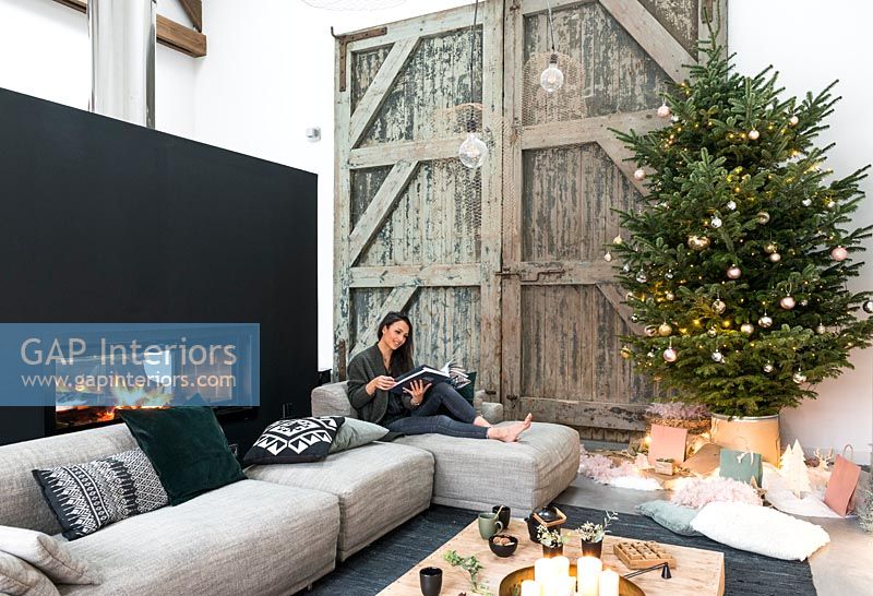 Femme lisant dans un salon de campagne moderne décoré pour Noël