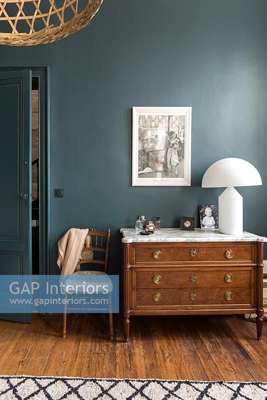 Commode en bois classique dans une chambre moderne avec des murs peints en turquoise
