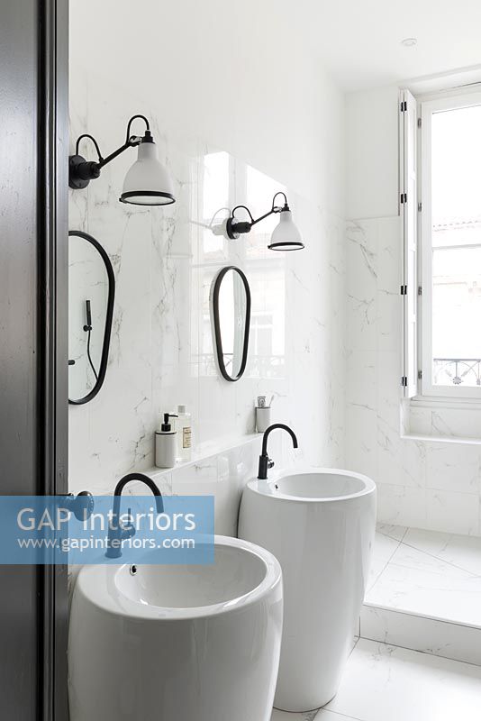 Lavabos doubles dans la salle de bain blanche moderne avec robinets noirs et cadres de miroir