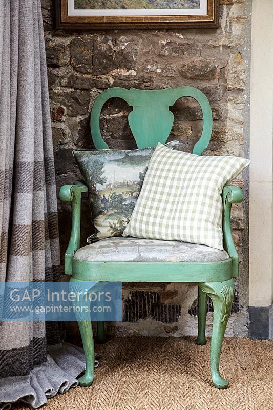Chaise en bois peint vert menthe contre mur de pierre