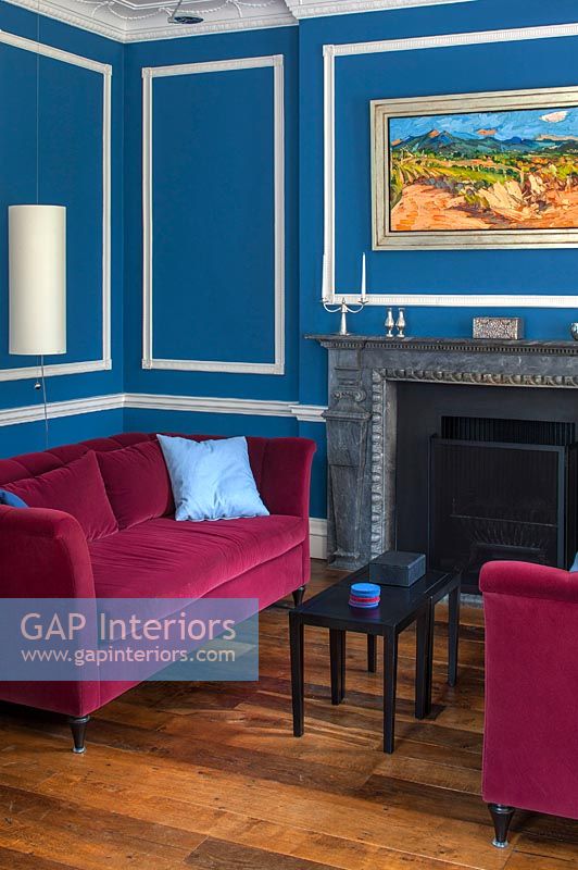 Murs peints en bleu azur et canapés en velours rose dans le salon classique