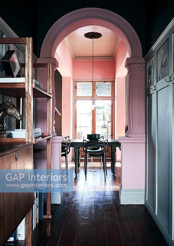 Vue à travers l'arche peinte rose à la table à manger