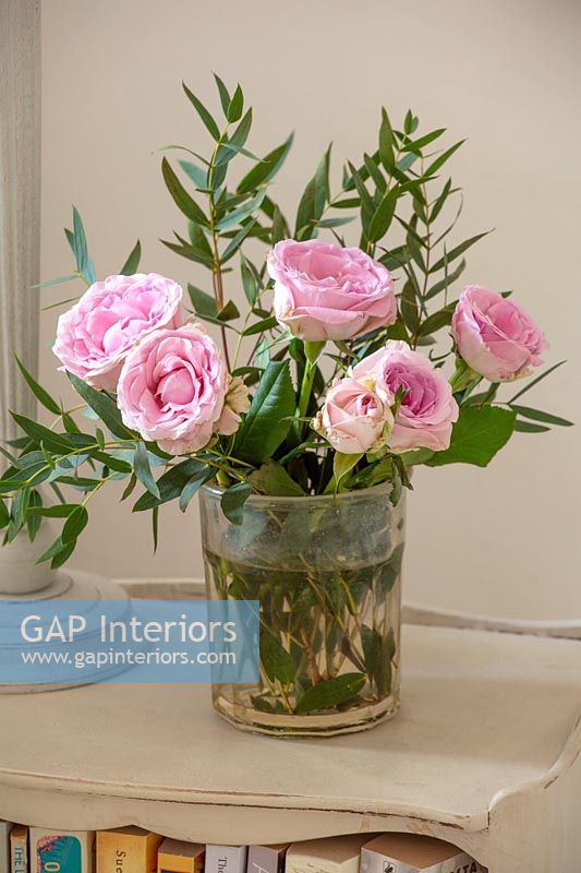 Roses roses dans un vase sur la table de chevet