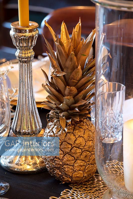 Ananas et argenterie pulvérisés d'or sur une table à manger classique