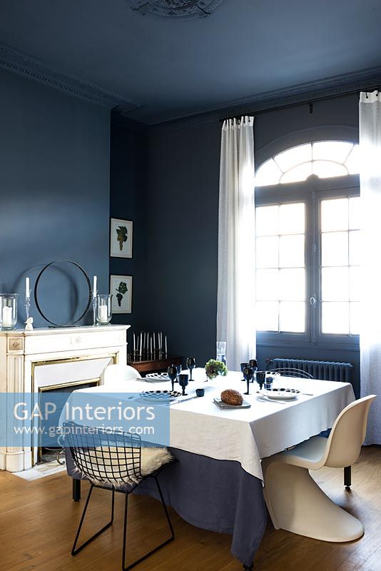 Salle à manger bleu foncé avec un mobilier blanc