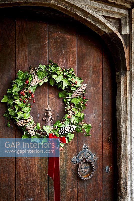 Gros plan d'une couronne de Noël sur la porte d'entrée en bois