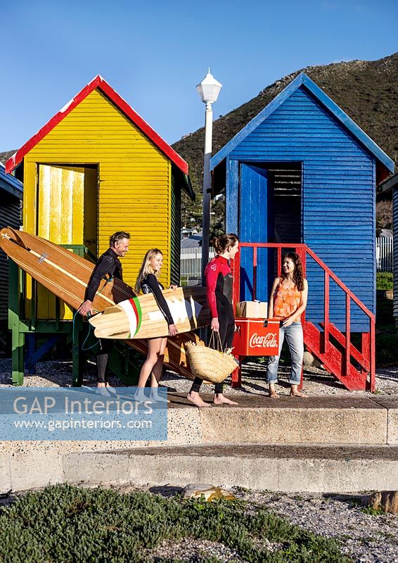 Surfeurs à côté de cabines de plage colorées